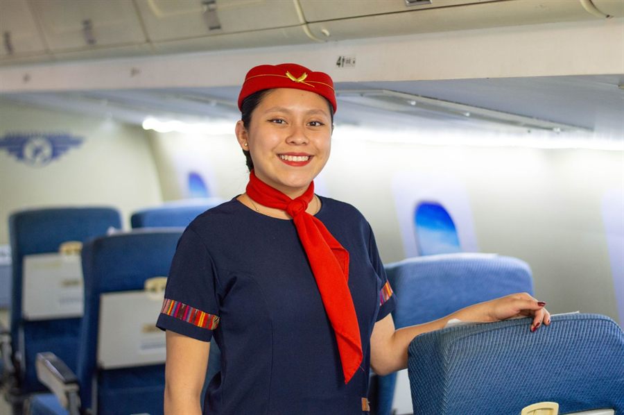 Smiling flight attendant in uniform standing in an aircraft cabin