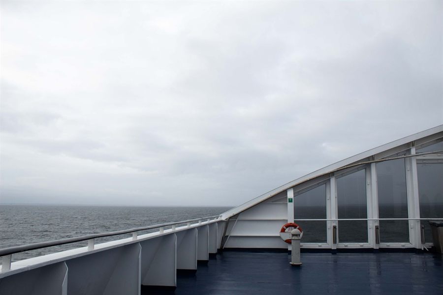 Ship&rsquo;s bow railing and an open grey sea