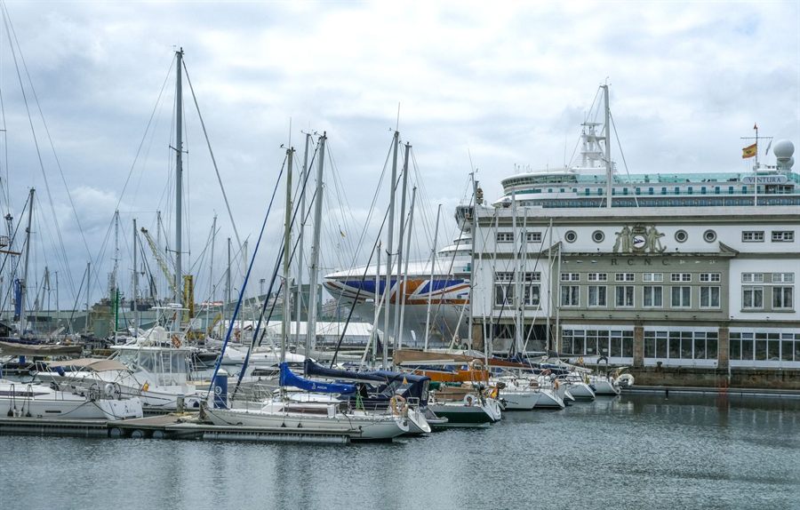 Sailboats in a marina with a passenger ship docked behind