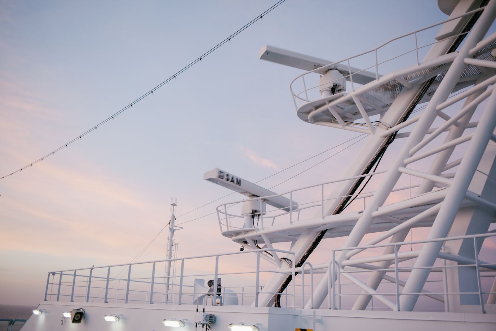 Upper deck of a ship with railings and masts at dusk, the kind of sailing travel agent cruise discounts help agents experience