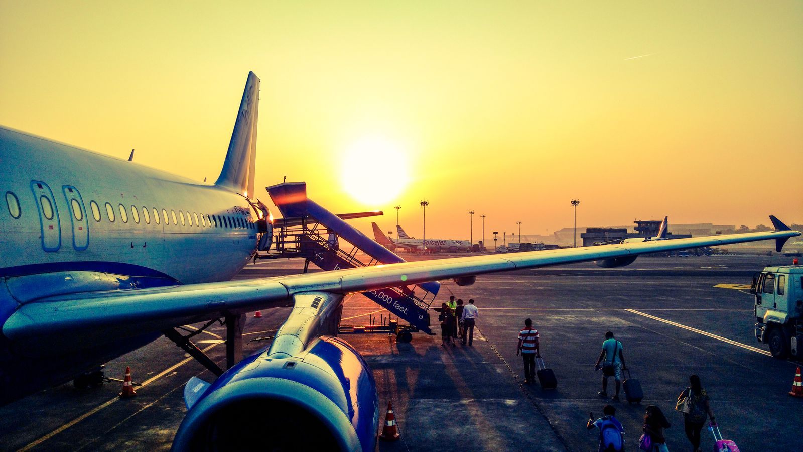 Passenger jet at an airport stand at sunset with boarding stairs, for airline staff using interline cruise discounts
