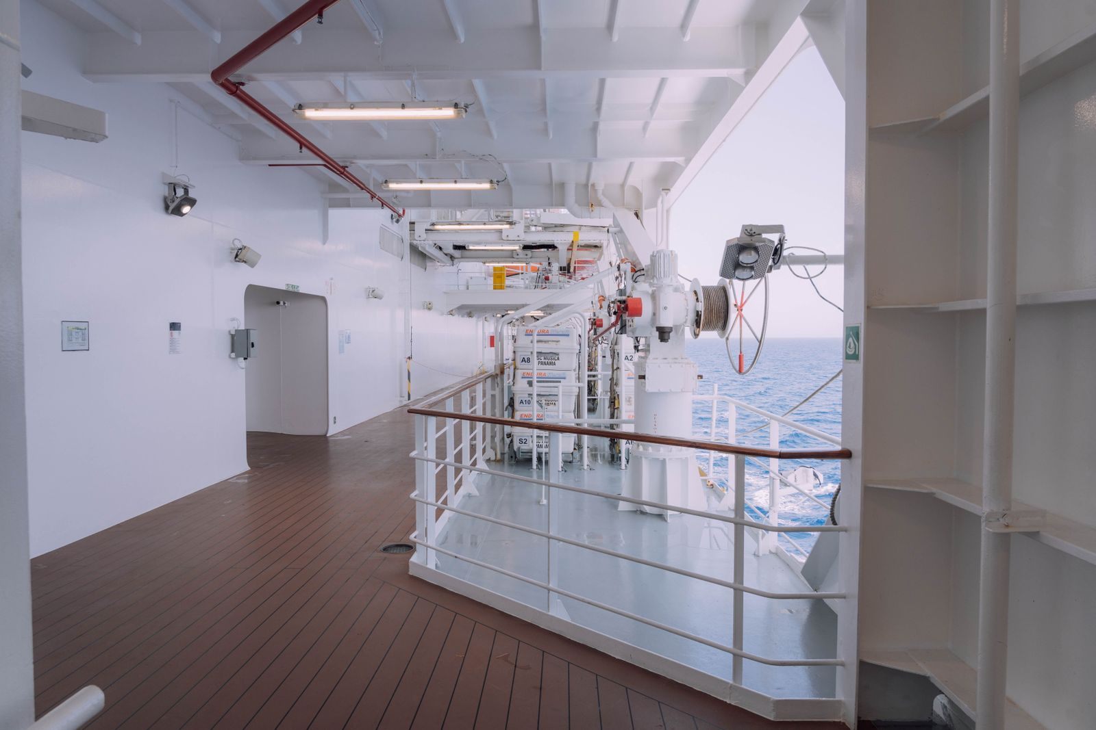 White outdoor promenade on a ship with teak deck and sea views, as on the cruise lines that offer travel agent rates